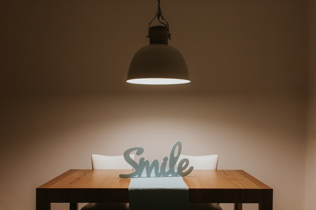 Positives Denken lernen - Smile als Wort auf einem beleuchteten Tisch